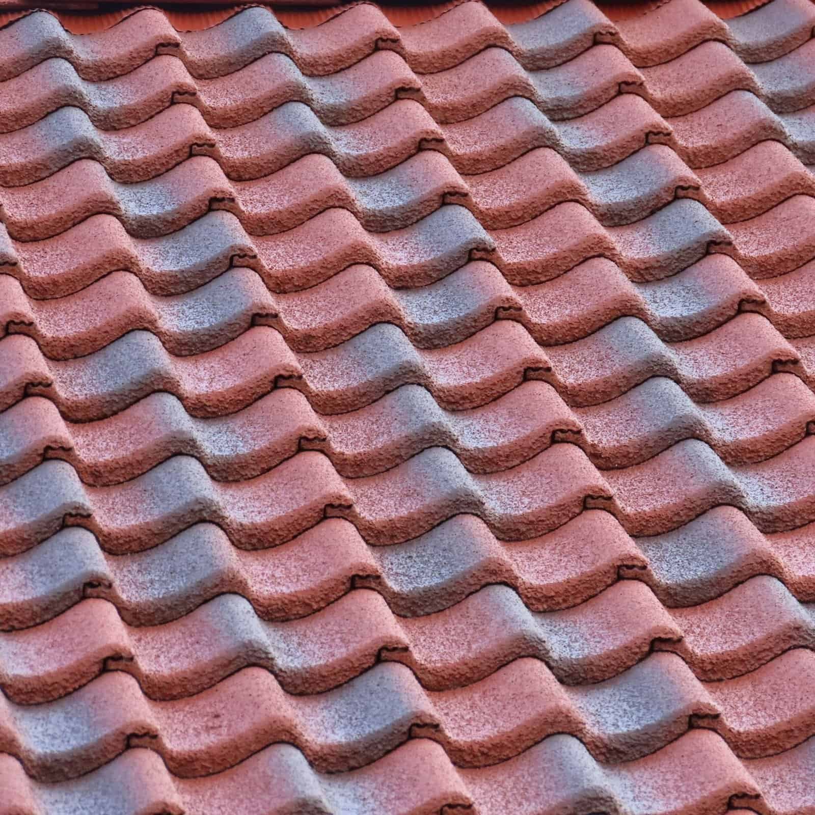 Close-up of red and gray textured roofing shingles with wavy pattern, durable and weather-resistant.